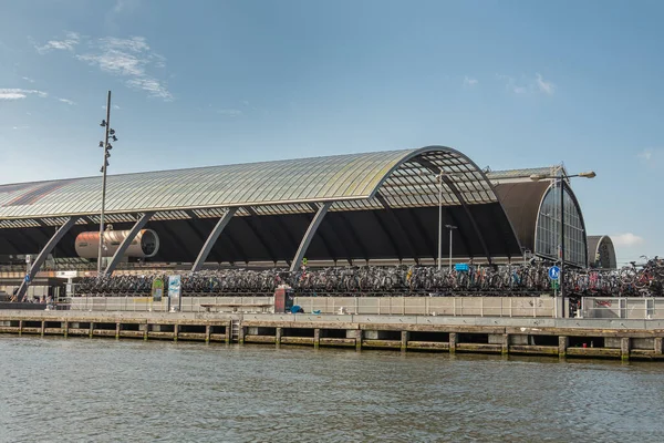 荷兰阿姆斯特丹 2021年8月15日 半圆形玻璃覆盖在铁路轨道上 在蓝天下的中央车站和前面的Ij河水下 停放的自行车数量 — 图库照片