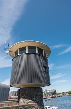 Amsterdam, Hollanda - 15 Ağustos 2021: NeMO bilim merkezi arkasında mavi bulutlar altında köprü bekçileri için gözcü kulesi.