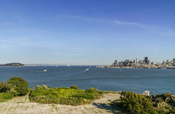 カリフォルニア サンフランシスコ 2007年5月6日 アルカトラズ島から オークランドベイブリッジと深い青い湾の水の後ろの薄い青い空の下の都市の街並み — ストック写真