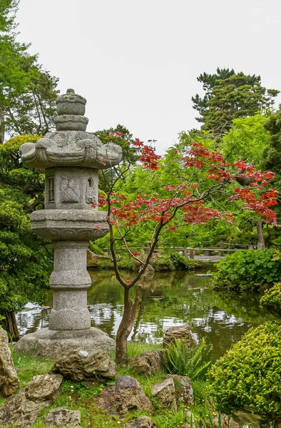 2008年5月19日 アメリカ カリフォルニア州サンフランシスコ 日本庭園 緑と赤の葉の色合いが異なる銀の空の下の池の近くに置かれた灰色の切石灯籠像 — ストック写真