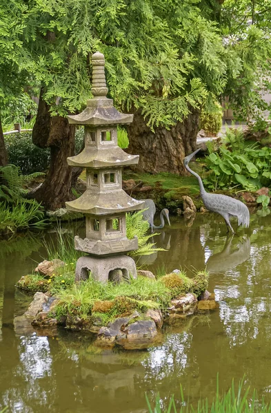 2008年5月19日 アメリカ カリフォルニア州サンフランシスコ 日本庭園 灰色の鶴鳥の像と緑の水の池に設定された灰色のカット石塔スタイルのランタン像 緑の葉 — ストック写真