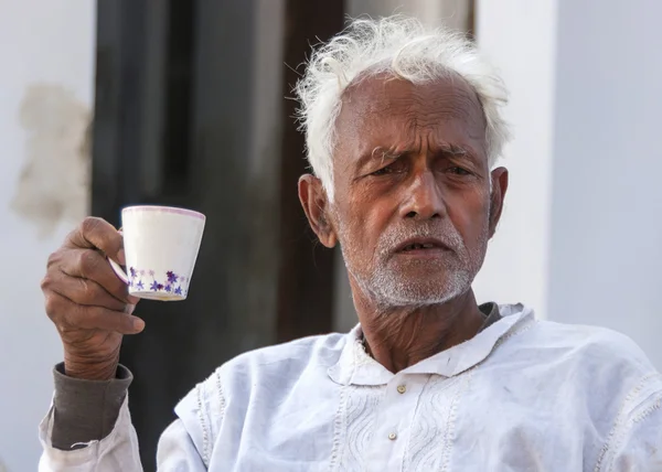 Oudere man met witte haren drinkt koffie. — Stockfoto