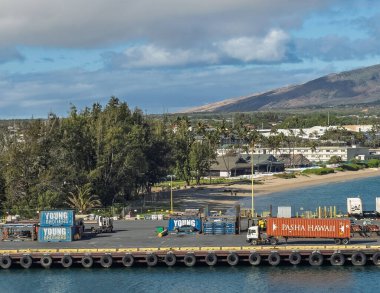 Kahului, Maui, Hawaii, USA - July 14, 2025: Harbor container parking with truck on dock at end of Wharf Street. Cityscape and mountain range west of the dock