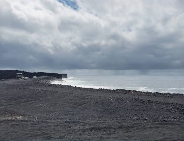 Pahoa, Hawaii Island, Hawaii, USA - July 15, 2025: Pohoiki Black Sand Beach landscape with white surf  crashing ocean waves under heavy gray-blue cloudscape