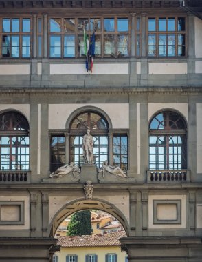 Firenze, İtalya, Avrupa - 14 Temmuz 2024: Müze heykeli ve bayraklarının iki kanadını birleştirmek için Uffizi Galerileri köprü binası. Kemerde, Arno nehrinin karşısındaki binalar.