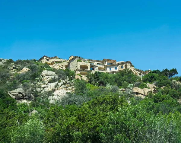 Porto Cervo, Sardinya, İtalya - 15 Temmuz 2024: Kosta Smeralda 'daki lüks tatil köyü. Limanın üstündeki tepelerde büyük bir malikane.