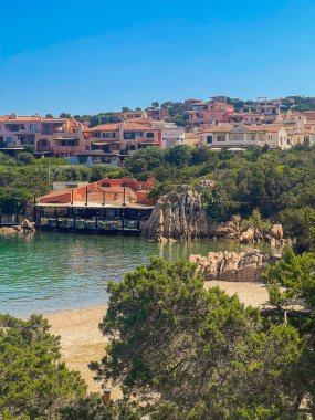 Porto Cervo, Sardinya, İtalya - 15 Temmuz 2024: Kosta Smeralda 'daki lüks tatil köyü. Quattro Passi al Pescatore restoranı ve Riviera 'nın altındaki otel. Ağaçlar ve mavi gökyüzü
