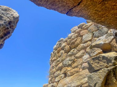Arzachena, Costa Smeralda, Sardinya - 15 Temmuz 2024: Nuraghe La Prisgiona, nuragic arkeolojik alan. Harap olmuş eşik: Mavi gökyüzüne karşı kaya parçaları