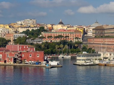 Napoli, İtalya - 17 Temmuz 2024: Liman manzarası. Donanma binasının solunda küçük bir marina var. Volaviamara ofisi sağda. Arkasında uzun bir bina var, Via Cesario Konsolunda duruyor. Şehir manzarasında 2 kilise kubbesi