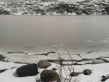 Kirkenes, Norveç - 26 Aralık 2025: Jentoftbukta körfezi çevresindeki doğa, kısmen donmuş. Kıyı şeridindeki bozuk daireler
