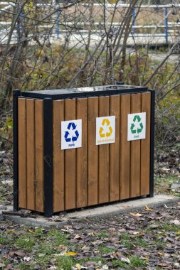 Bir geri dönüşüm istasyonunda kağıt, plastik ve metal için etiketlenmiş üç kutu yer alır. Macaristan 'ın Szigetszentmiklos kentindeki bir parkta yere düşen yapraklarla sonbahar manzarası sergilenmektedir..