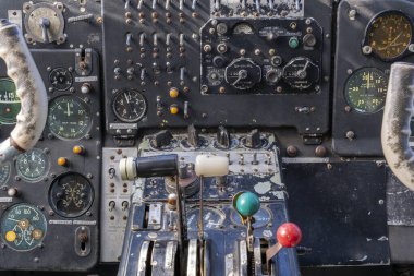 Eski bir Antonov uçağı açık bir alanda duruyor. Açık mavi gökyüzü arka planı dolduruyor ve uçağın görünür bir pervanesi ve motoru var. Bir serginin parçası gibi görünüyor..