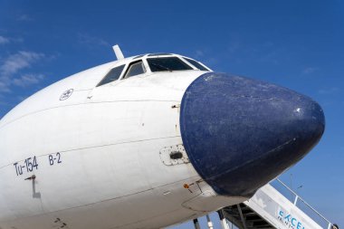 Havaalanına bir TU-154 uçağı park edilmiş ve girişe giden merdivenler var. Uçağın burnu parlak mavi bir gökyüzünün altında açıkça görülebilir. Yer hareketliliği yakınlarda..