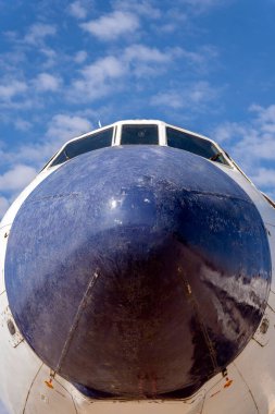 Bir TU-154 uçak burnu açık mavi gökyüzü ve kabarık beyaz bulutlarla gösterilir. Uçak sabit, dizaynını ve yapısını düşük açıyla vurguluyor..