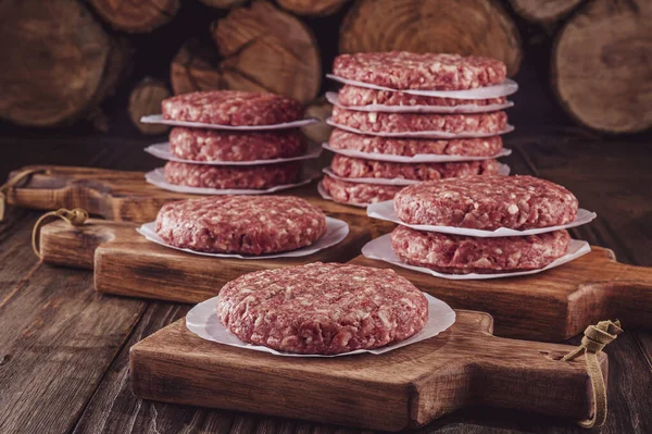 Tahtayı kesen hamburgerler ahşap arka planda.