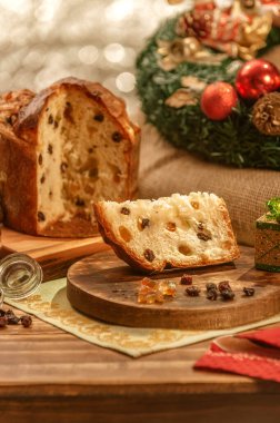 Bir dilim panettone ve tahta kesme tahtasının üzerinde şekerli meyve küpleri noel süsleri.