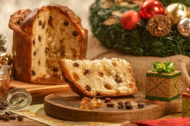 Bir dilim panettone ve tahta kesme tahtasının üzerinde şekerli meyve küpleri noel süsleri.
