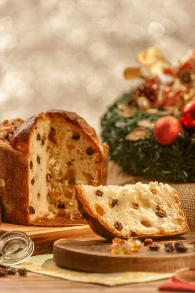 Bir dilim panettone ve tahta kesme tahtasının üzerinde şekerli meyve küpleri noel süsleri.