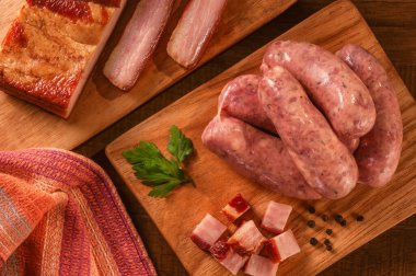 Tahtanın üzerinde çiğ Brezilya pastırması sosisi ve taze pastırma dilimleri var.