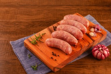 Brezilya domuz budu sosisi, ahşap arka planda izole edilmiş tahta kesme tahtasıyla sarımsak.