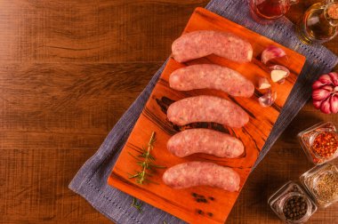 Brezilya domuz budu sosisi, ahşap arka planda izole edilmiş ahşap kesim tahtasına sarımsak.