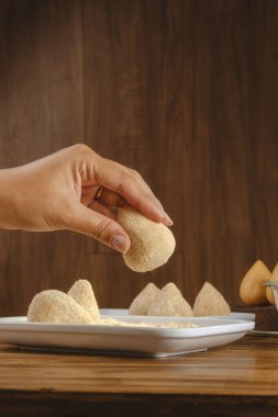 Brezilya kroketini (coxinha de frango) ahşap mutfak masasında eken kadının elleri