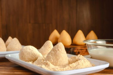 Brezilya usulü pişmemiş ekmek kroketleri (coxinhas de frango) ahşap mutfak masasında.