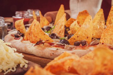 Mozzarella, soğan, pepperoni, siyah zeytin, yeşil biber, nachos ve kekikli pizza..