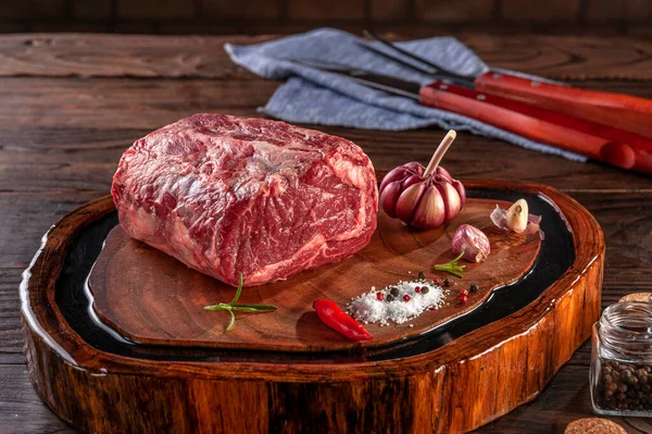 Raw entrecote beef on a wood cutting board with spices.