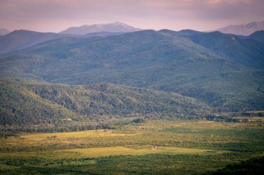 Sabahın erken saatlerinde dağlarda. Sabah güneşi ve sis vadinin arka planında dağların arkasında.