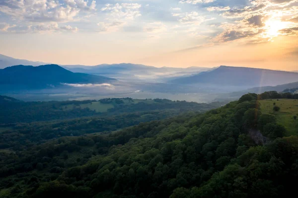 一大早在山上 晨阳和山谷中的薄雾映衬着群山的背景 — 图库照片