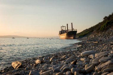 Kargo gemisi karaya oturdu. Çamurlu sahilde gün batımı