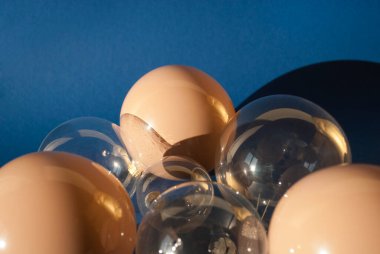 Uzun gölgeli koyu mavi arka planda bej ve şeffaf toplar. Yeni yıl ya da Noel konsepti. Kış tatili teması