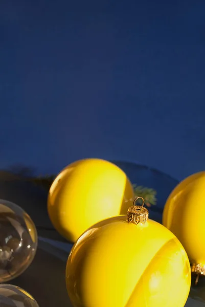 Decoration yellow and transparent balls on dark blue background with long shadows. New Year\'s or Christmas concept. Winter holiday theme. Space for text