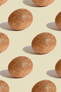 Paskalya deseni. El yapımı Paskalya yumurtası. Bej arka planda parıltılı altın yumurtalarla desen. Yatırım kavramı