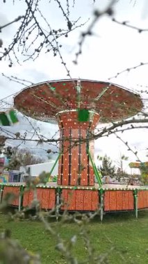 Bulutlu bir sonbahar gününde suya yansıyan çeşitli eğlencelerle dolu bir lunapark.