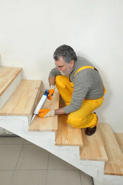 Renovación del hogar, calafateo de escaleras de madera con silicona — Foto de Stock