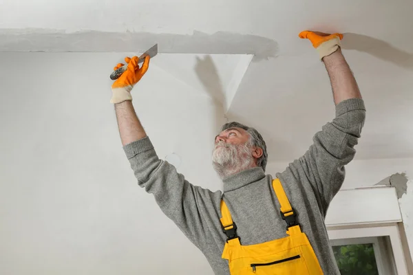 Arbetaren reparera gips på taket — Stockfoto