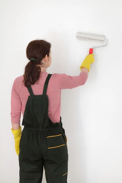 Joven trabajador pintar la pared en una habitación a blanco —  Fotos de Stock