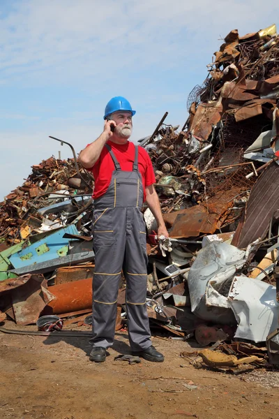 Industria del riciclaggio, operaio che utilizza il telefono e cumulo di metallo vecchio — Foto Stock