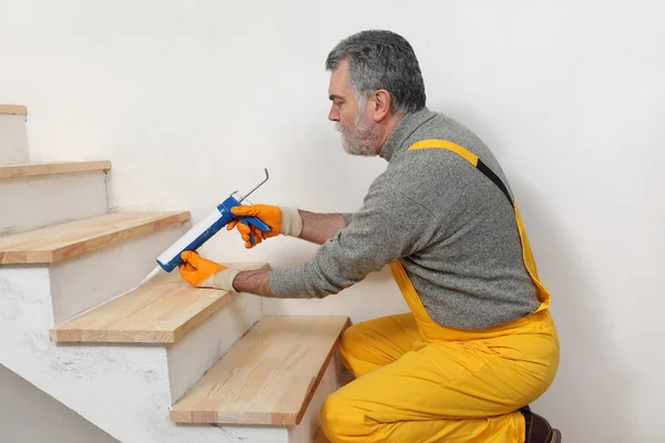 Renovación del hogar, calafateo de escaleras de madera con silicona — Foto de Stock