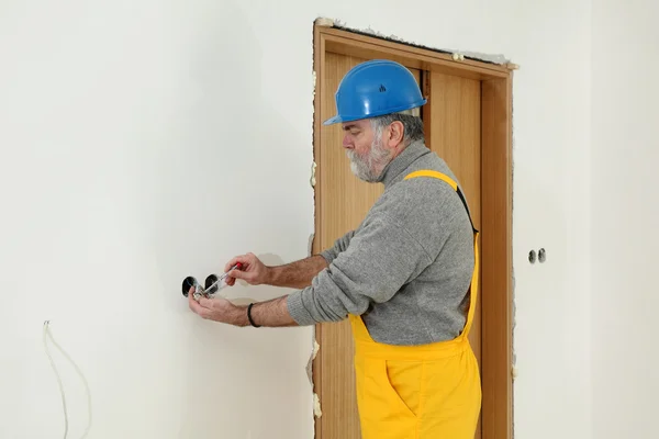 Electrician at construction site install electrical plug — Stock Photo, Image