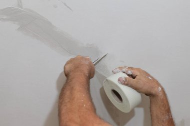 Tavandaki çatlakları onaran işçiler, lifin üzerine alçı serpiştiriyorlar.