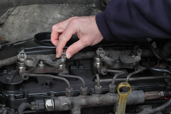 Worker fixing modern common rail diesel engine, closeup of hand placing electrical connector to injector