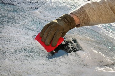 Kış sahnesi, insan eli eldivenle arabanın ön camından buz kazımak, sürücü alet kullanmak...