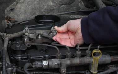 Modern demiryolu dizel motorunu tamir eden işçiler, ellerin enjektöre bağlanması için yakın plan
