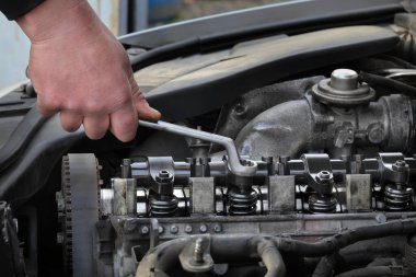 Araba tamircisi modern dizel motoru tamir ediyor, İngiliz anahtarıyla elinizi kapatıyorsunuz silindir başındaki enjektörleri söküyorsunuz.