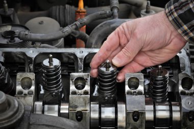 Araba tamircisi modern dizel motoru tamir ediyor. Elin kapatılması, enjektörleri silindir başından çıkarıyor.