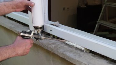 İşçi yeni plastik pencere kuruyor, tabancalı poliüretan köpük kullanıyor