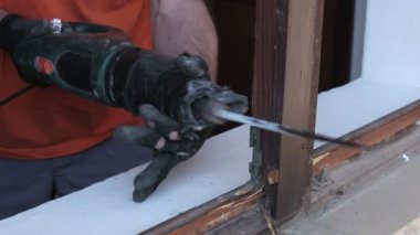 İşçi elektrikli testereyle eski pencereyi kesip yok ediyor